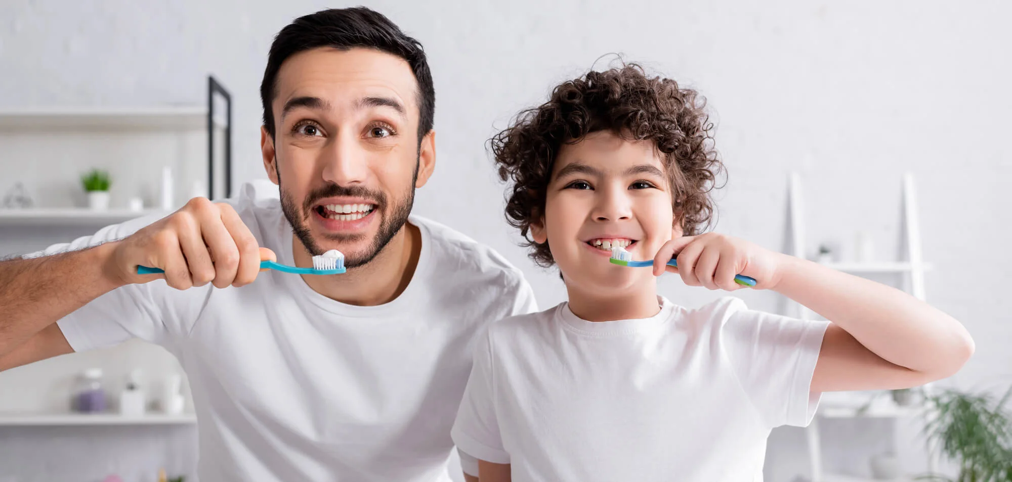 Father and child brushing teeth together, smiling happily Routine dental care New Jersey (1)